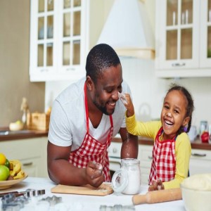 a father laughing and cooking with his daughter.
