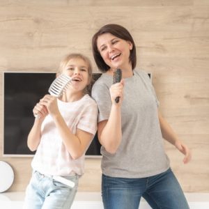 Mother singing to hairbrush with daughter.