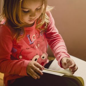 Young girl turning the page of a book.