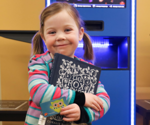 Child holding a library book and library card
