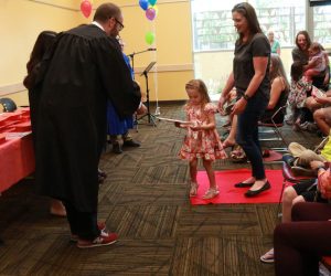 Woman and child accepting "1000 Books Before Kindergarten" diploma from a library staff member