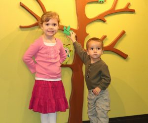 Boy and girl in front of the "1000 Books Before Kindergarten" tree