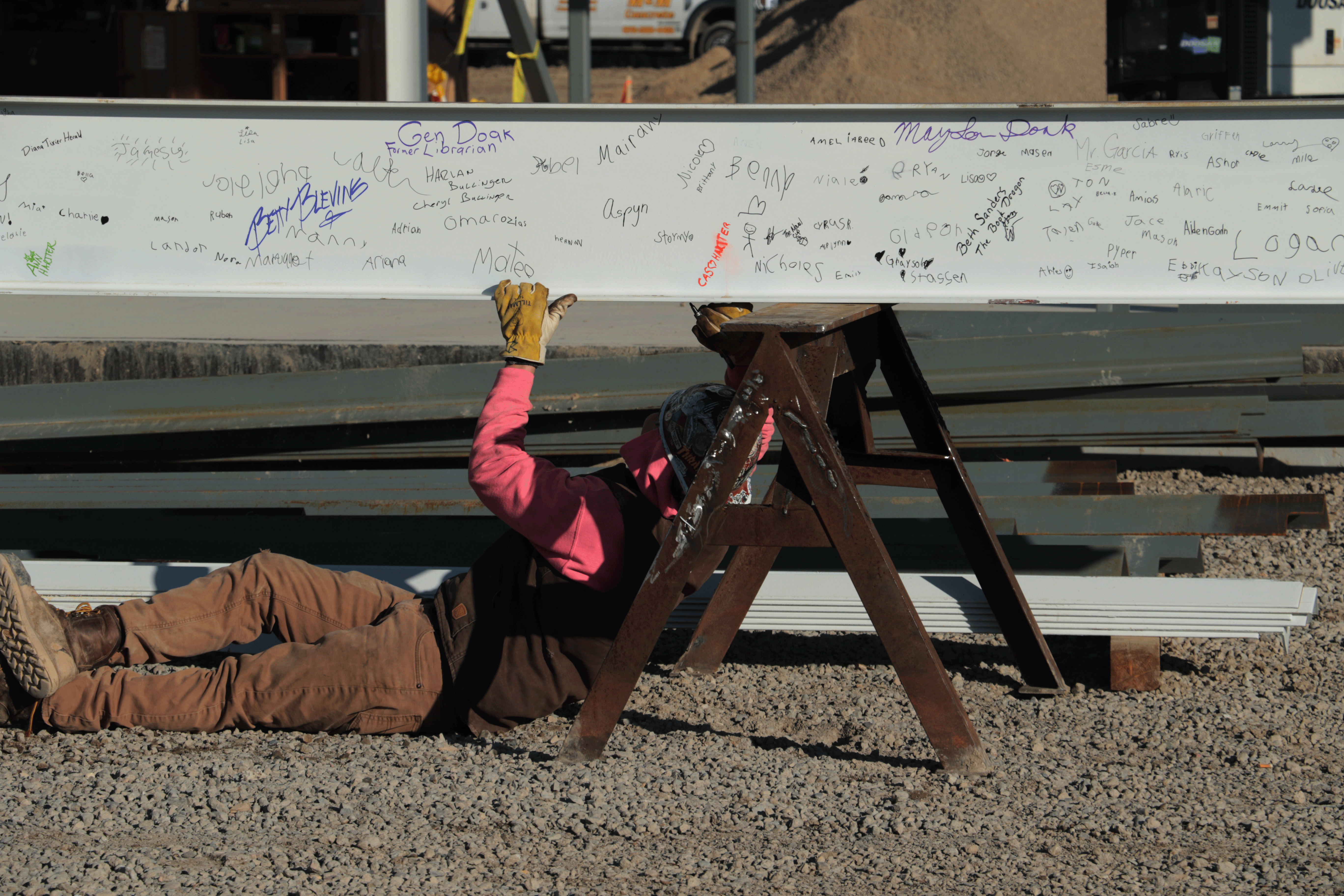 Construction worker signing the bottom of the steel beam at the beam signing