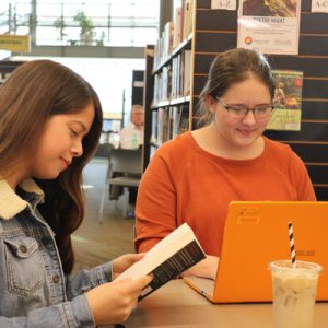 two teens sitting at a library table