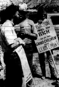 Photo I.D. - Black and white image of protesters with picket signs. The only visible sign reads "Rulison will make you rich but will our grandchildren have leukemia?"