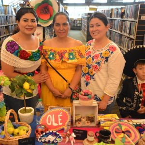 Three adults and a child in traditional Mexican dress stand in front of the Mexico information table
