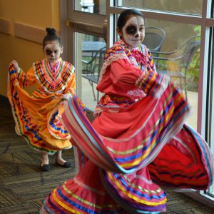 Two young girls in traditional Mexican dress dancing
