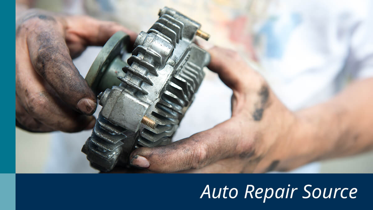 Greased hands holding an alternator.