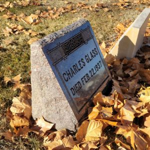 Photo depicting Charlie Glass's headstone in Elmwood Cemetary, Fruita Colorado. It is marked "Charles Glass: Died Feb. 22, 1937" and has a floral design on the upper edge.