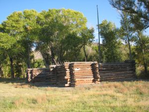 Color photograph of a reconstruction of Pike's Stockade. It is a small wooden structure built in a log-cabin style. 