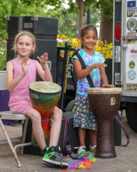 two young girls play hand drums
